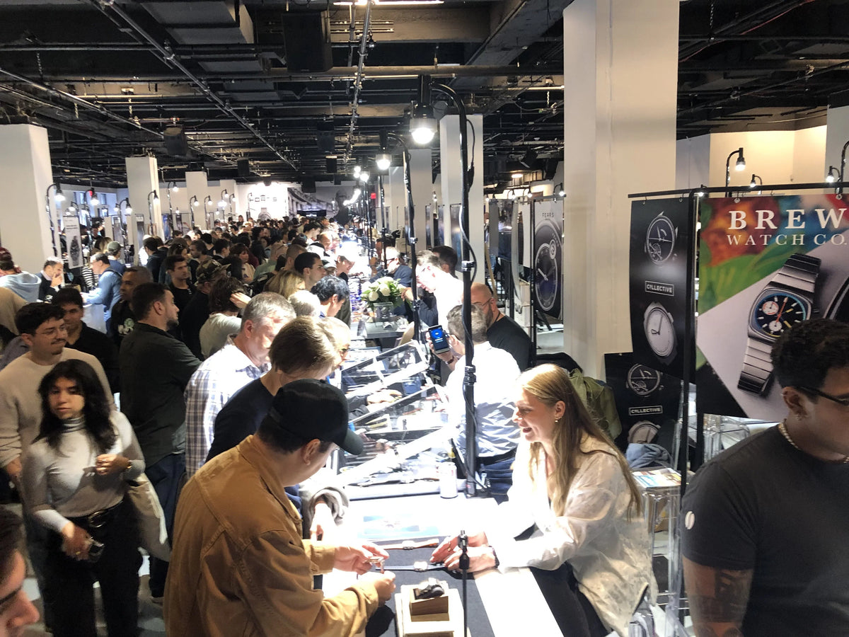 Visitors browsing watch display counters in a busy indoor exhibition hall